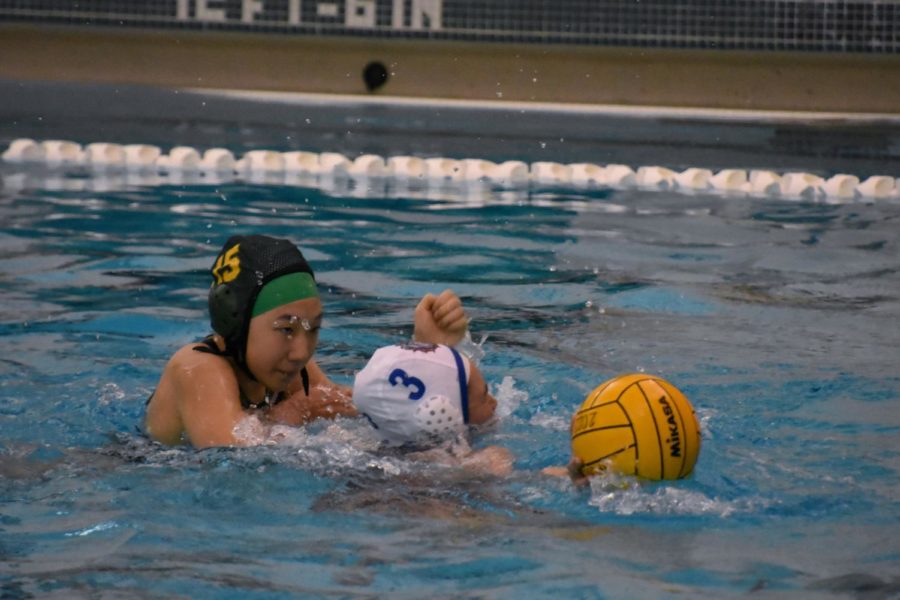 Sophomore Briana Kim steals the ball from an opposing offender and makes a breakaway during a game against Mason on April 11. “I swam away from her because she was on my shoulders, I nudged her off and swam to the other side where she couldn’t get to me; I got open water, started treading and then shot the goal,” Kim said.