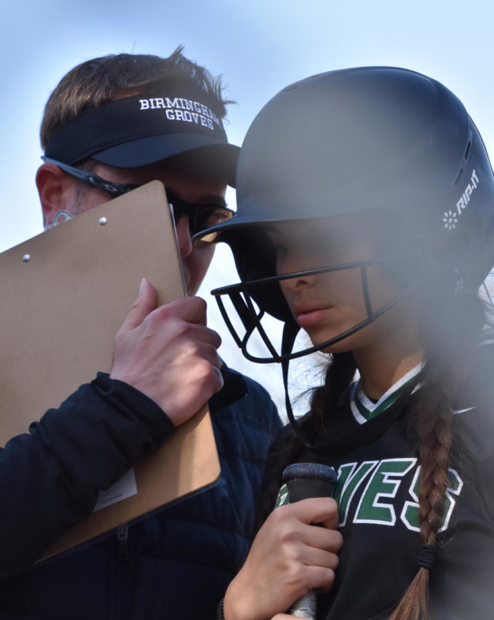 Senior first baseman Ellie Kroll is concentrating on getting a hit while getting advice from her varsity coach Brian Baldridge on April 28  “ He shows us videos that symbolize us as a team and even though people don’t see us as the best we have to play like we’re the best because Coach tells us all the time he sees something in us, we just have to believe it. 