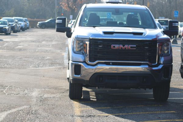 A GMC car parked not only on a segment of yellow, horizontal striped lines in the Groves student parking lot— indicating that the space is not a parking spot— but parked so that their tire and mirror are protruding upon the path of other cars driving by. Disregard for parking lot etiquette (and rules) is a common issue at Groves. 