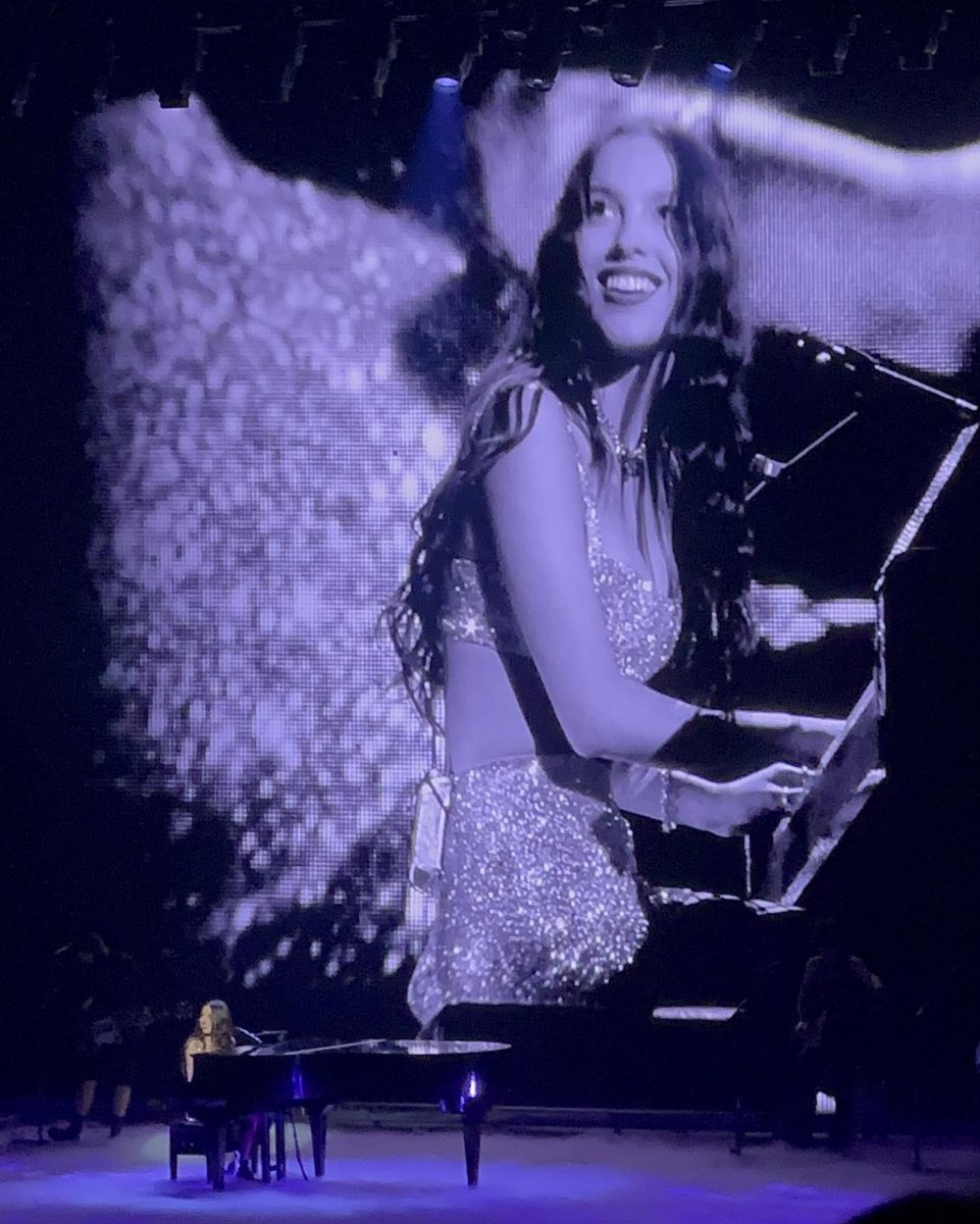 Olivia on stage playing the piano while performing her hit song, “drivers license” 
