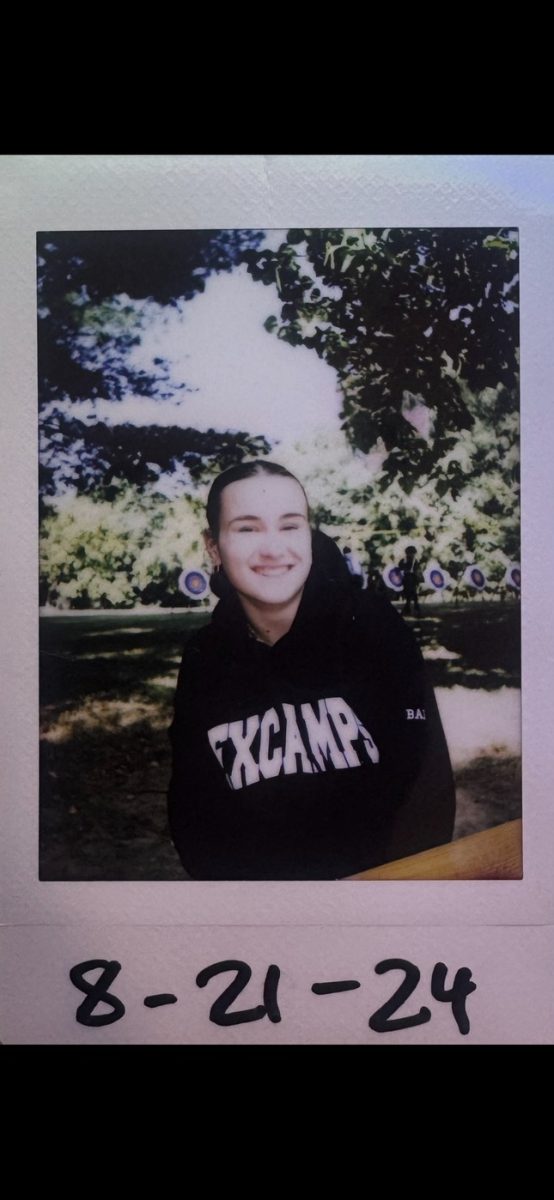 A polaroid of Baity Wagner at Experience Camps, sitting at a picnic table.