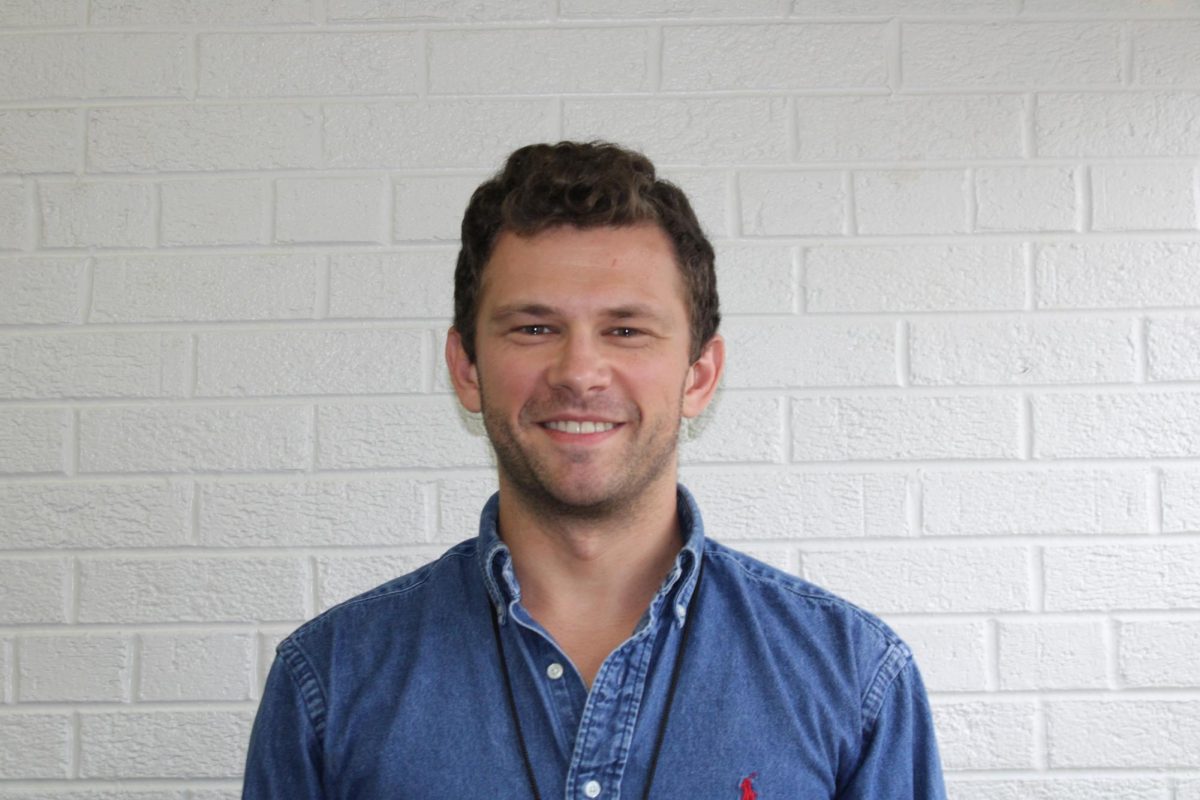 New Social Studies teacher, Hunter Janness, posing for a photo in the hallway.
