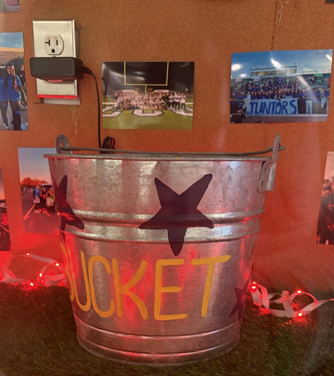 The prize won at Field Day, which is a decorated bucket. The bucket is shown in the school display case, and it is surrounded by Field Day photos.
