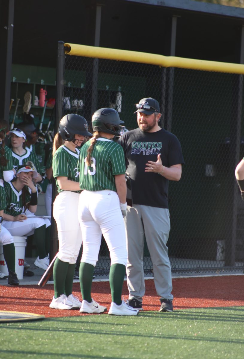 Groves sophomores Kinley Roy and Charlotte Gress talking to their coach outside the dugout.